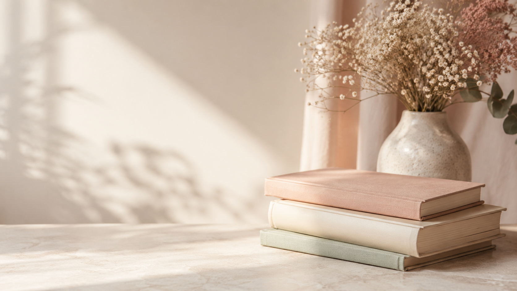 Livres empilés et vase de fleurs sur un bureau clair